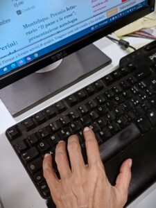 immagine parte di tastiera e monitor con porzione di mano