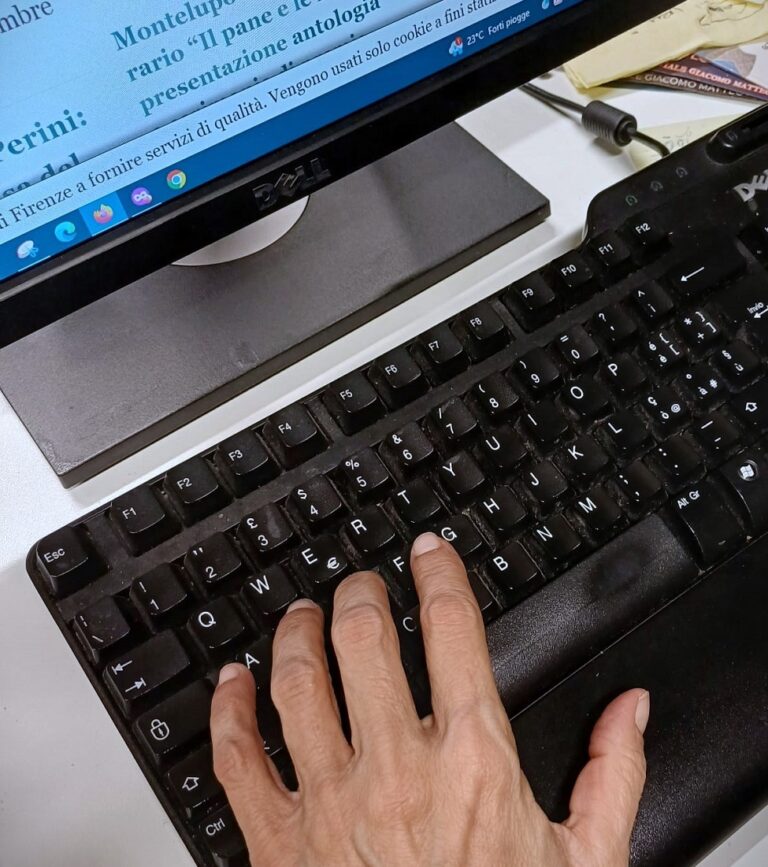 immagine parte di tastiera e monitor con porzione di mano