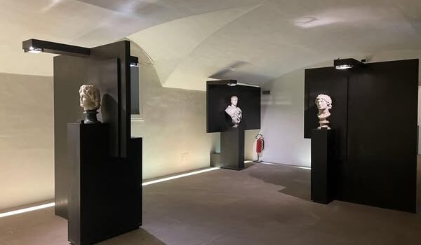 visione trasversale di una sala del museo, tre teche nere contenenti ciascuna un busto di marmo