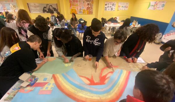 studenti intorno a un tavolo disegnano un arcobaleno